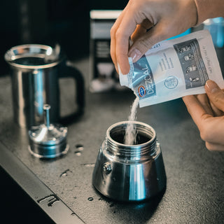 Dezcal descaler powder being poured into coffee equipment