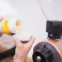 Grindz tablets being poured into a commercial coffee grinder hopper
